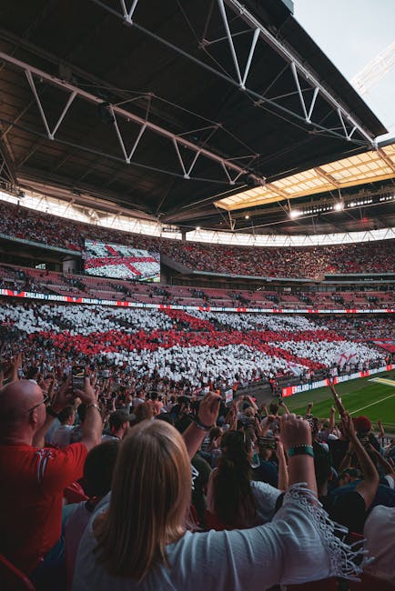 The image shows the interior of Craven Cottage stadium during a match day, with red stadium seats arranged in tiers and a few blue seats scattered among them. The seats are mostly unoccupied, with som